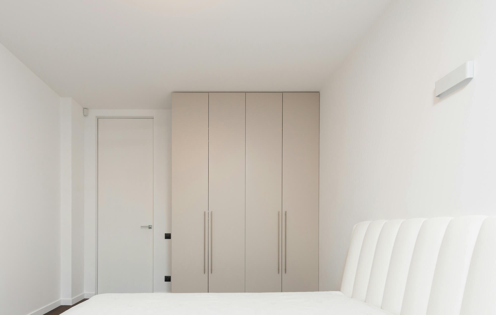 PAX Schrank mit cremefarbenen Schranktüren in weißem Schlafzimmer